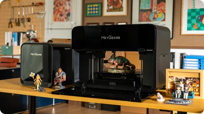 HeyGears G1 Series printer on a workbench with colorful sample figures around it