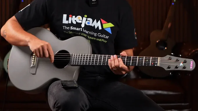 A musician holding the grey LiteJam Neo A1 with coloured fretboard lights illuminated